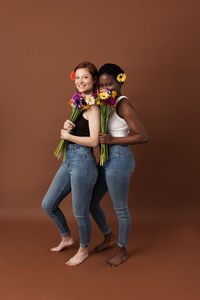 Portrait of young couple standing against gray background