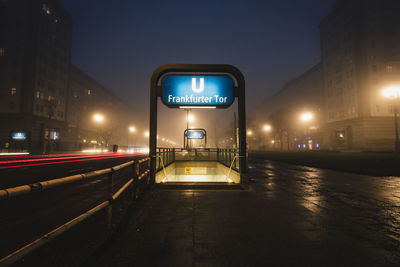 Illuminated road sign on street in city at night