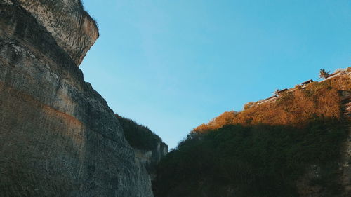 Low angle view of rocks against clear blue sky