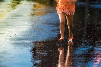 Low section of girl on wet street during rainy season