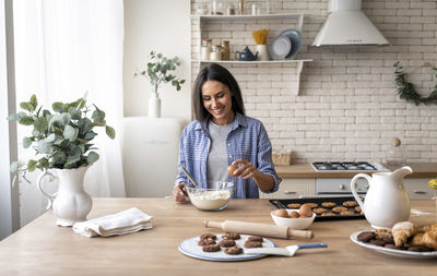 Young woman preparing food on table at home