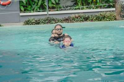 Family wearing goggles and swimming together in the pool.