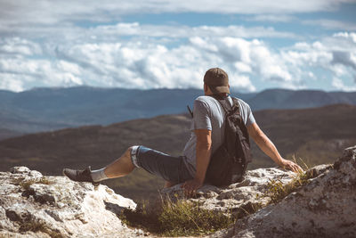 Side view of man sitting on rock