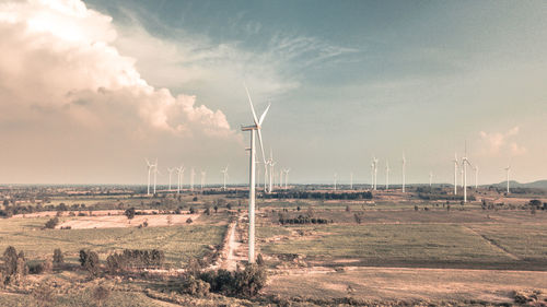 Scenic view of windmills on field against sky