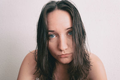 Portrait of young woman with messy hair against wall