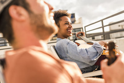 Young couple with beer and guitar on a rooftop party