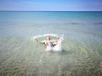 Man surfing in sea against sky