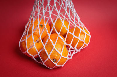 Eco-friendly mesh with tangerines on a red festive background. feast of the nativity of christ.