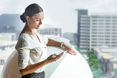 Young woman using mobile phone in city