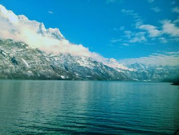 Scenic view of sea and mountains against blue sky