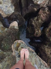 Low section of woman standing on rock at beach