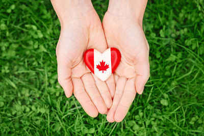 Human hands holding wooden heart with canadian flag symbol. canada day national celebration 