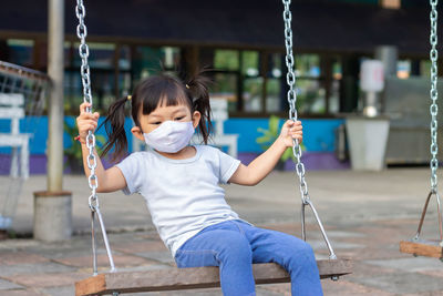 Girl sitting on swing at playground