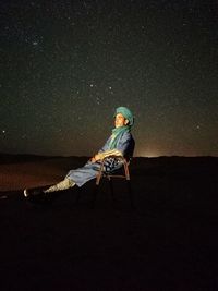 Man sitting on chair against star field