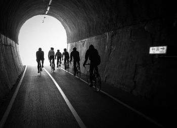 Rear view of people riding bicycle in tunnel