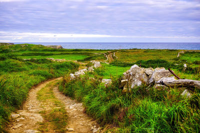 Scenic view of land by sea against sky