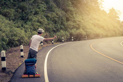 Full length of hiker hitchhiking on country road