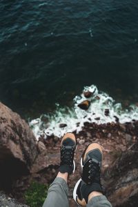 Low section of man on cliff over sea