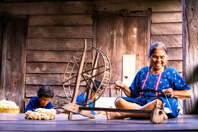 Smiling senior woman working on loom at home