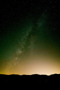 Scenic view of silhouette mountains against star field