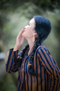 Young woman looking away while standing outdoors