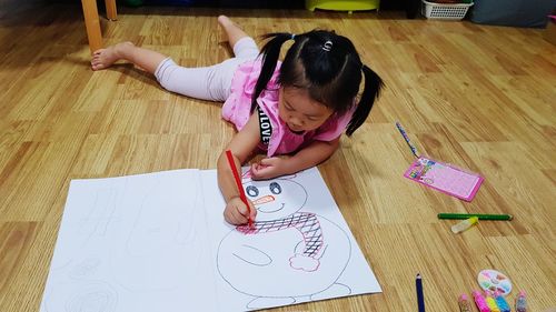 High angle view of cute girl lying on floor at home