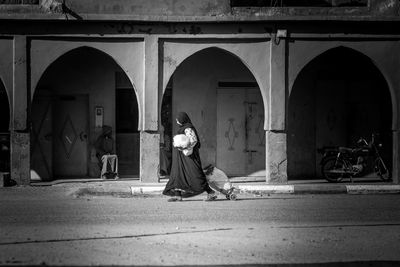 Side view of woman sitting outside building