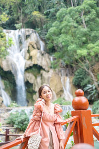 Portrait of smiling young woman standing against mountain