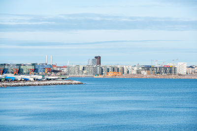 Sea by city against sky