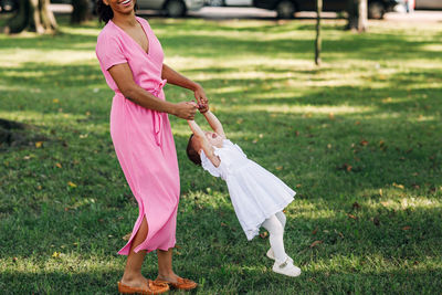 Full length of woman with pink umbrella on field