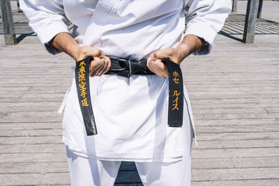 Karate man tying the knot of his black belt