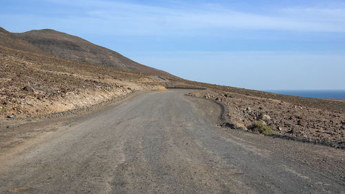 Scenic view of road by mountain against sky