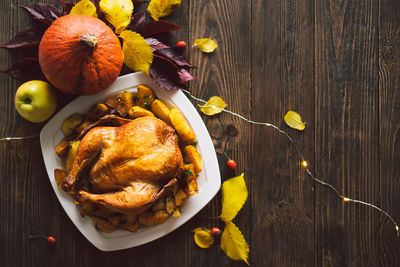 Autumn composition with leaves, ripe pumpkin and thanksgiving turkey on a dark wooden table.