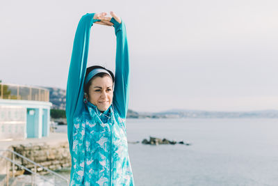 Portrait of smiling young woman standing against sea