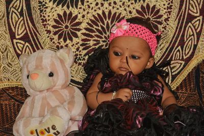 Cute girl with toy relaxing by stuffed toy on sofa at home