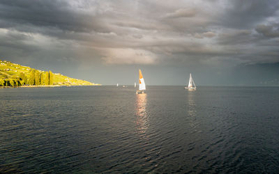 Sailboats in sea against sky