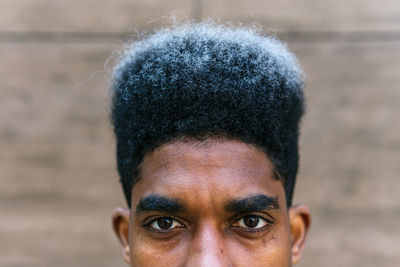 Crop determined african american male with dyed curly hair standing in city and looking at camera