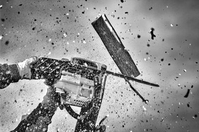 Cropped of hand of person cutting wood with chainsaw in mid-air