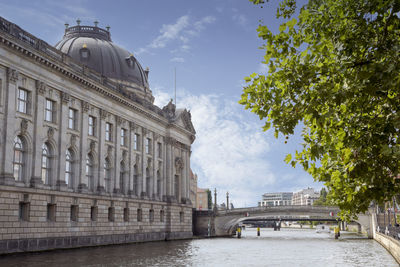 View of buildings by river against cloudy sky