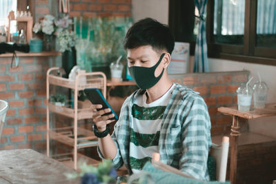 Young man using mobile phone at table
