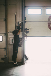 Female worker opening shutter of distribution warehouse