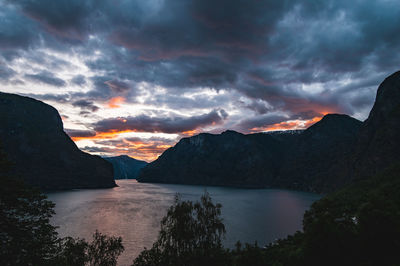 Scenic view of lake by mountains against sky during sunset