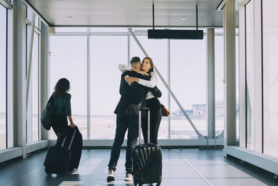 Businesswoman walking by colleagues greeting in corridor at airport