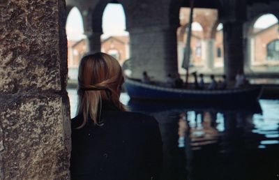 Rear view of woman standing by canal