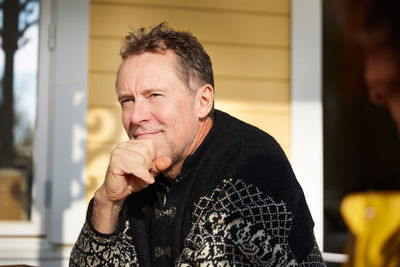 Thoughtful mature man looking away while sitting on porch