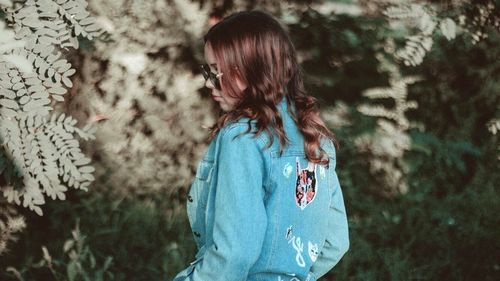 Rear view of woman standing against trees