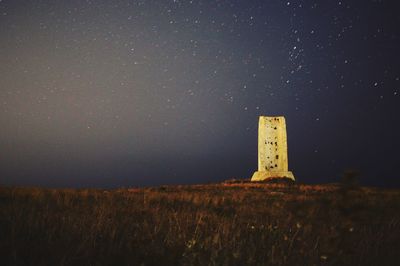 Lighthouse on field against sky at night