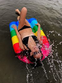 High angle view of young woman lying on pool raft in lake