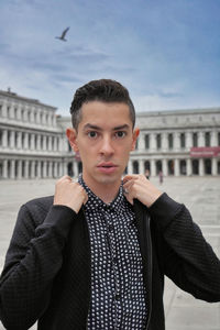 Portrait of young man standing against sky
