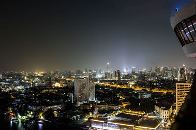 Illuminated modern buildings in city against sky at night